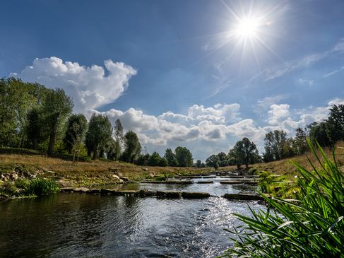 Zu sehen ist die Sohlgleite und die Ufer der Vechte. Der Blickwinkel und die Sonne verleihen dem Bild eine beruhigende Stimmung.