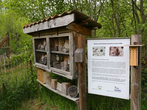 Das Bild zeigt ein Insektenhotel und eine Info-Tafel