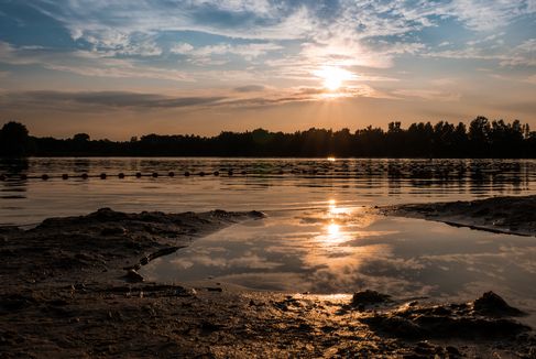 Wunderschön geht die Sonne unter und spiegelt sich dabei im Wasser des Quendorfer Sees und zaubert dabei ein tolles Lichtspiel in das Wasser.