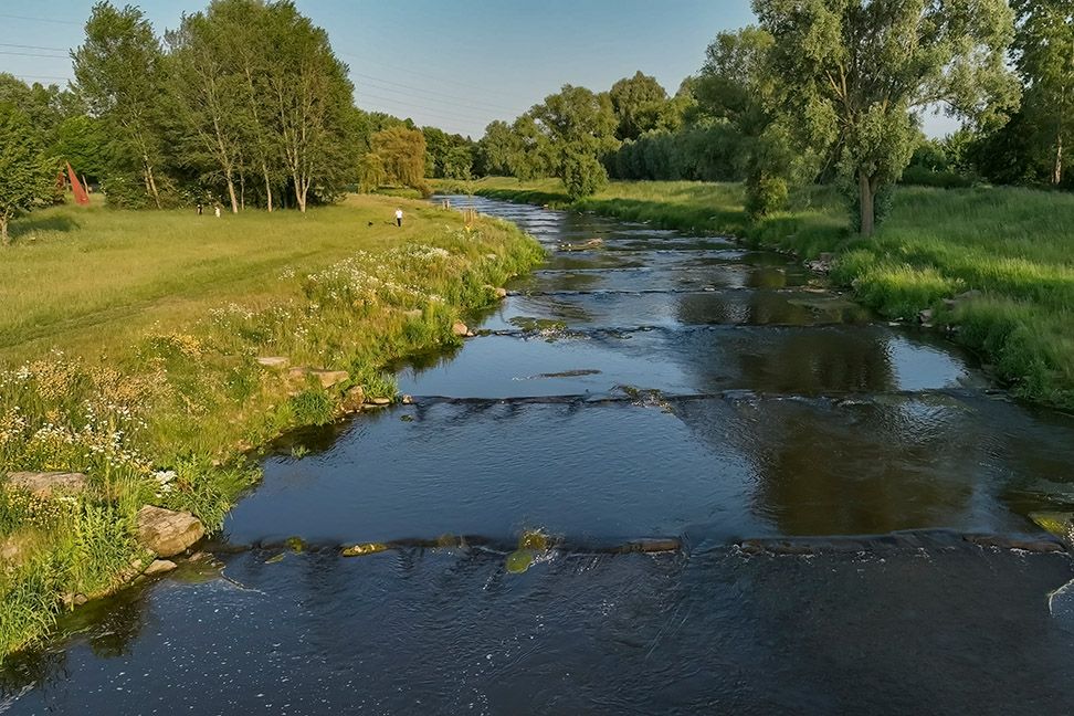 Die Sohlgleite bei Sonnenschein und grünen Ufern Fluss aufwärts.