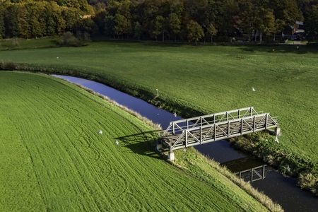 Eine ehemalige Eisenbahnbrücke steht mitten auf zwei Feldern, über der Vechte und verbindet an dieser Stelle zwei Bundesländer miteinander.