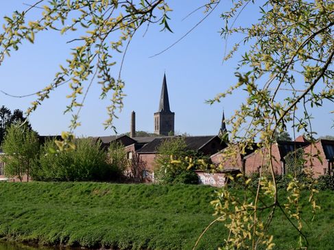 Zwischen blühenden Bäumen hindurch ist von Weitem die Stadt Schüttorf mit ihrem charakteristischen Kirchturm zu sehen.